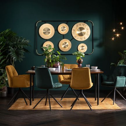 Magnifique chaise look velours de couleur jaune avec accoudoir Mila de la marque Kare Design exposé dans une salle à manger avec des autres chaises de couleur vert canard