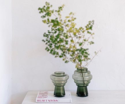 Sublime vase tendance en verre de couleur vert sapin de la marque Andrea exposé sur une table avec des fleurs